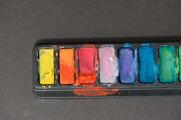 palette of pan paints on a grey background