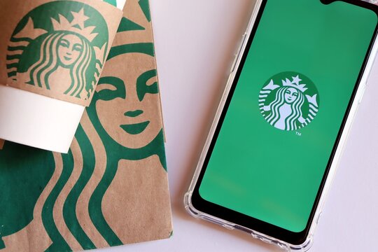 Bahia, Brazil - September 30, 2020. Starbucks app on smartphone screen, shopping bag and Starbucks cup. 