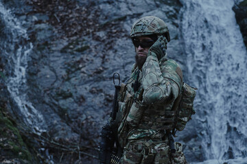Fototapeta premium Portrait of airsoft player in professional equipment with machine gun in the forest. Soldier with weapons at war