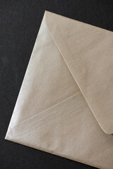 verso of a pearl finished iridescent tan envelope on dark grey
