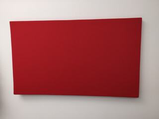 Piece of art on a white wall in a museum with nothing but plain red surface paint