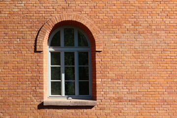 Fototapeta na wymiar Arched glass window in red brick wall. Window in a red brick wall house