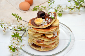 pancakes and branches of blossoming cherry on the table