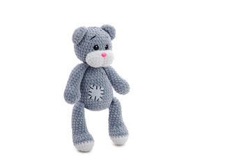 Plush crocheted grey bear toy with patch stands on white background. Soft toy. Handmade. Stuffed animals