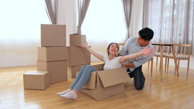 Happy Couple Is Having Fun With Cardboard Boxes In New House At Moving Day
