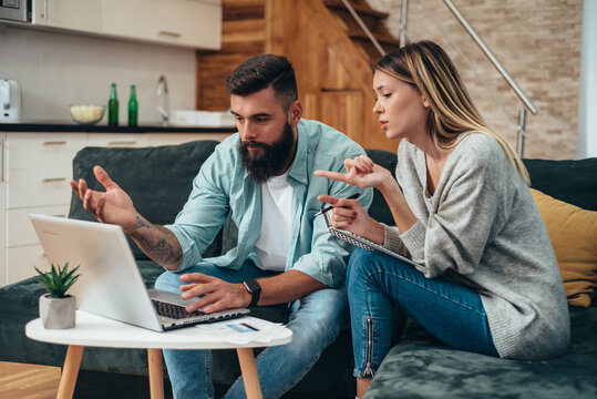 Young beautiful couple using a laptop calculating their finances at home
