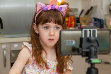 Baby Girl In A Kitchen Looking At A Mobile Phone
