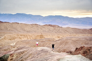 Fototapeta na wymiar A family with a teenage girl is hiking Dante’s View trail in Death Valley National Park in California, USA during their road trip from Las Vegas to San Francisco in March 2021 during COVID-19 pandemic