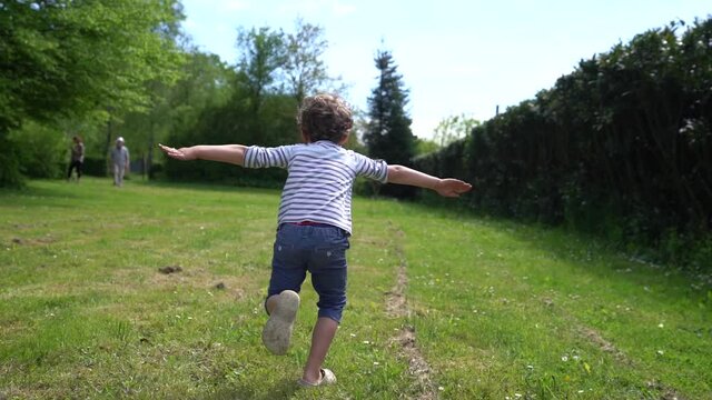 un petit gar&ccedil;on qui fait l'avion en courant dans un pr&eacute;, au ralenti