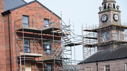 Scaffolding surrounding new house and church for safe access to construction work