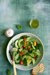 Fresh vegetables salad with spinach, avocado, cucumber and cherry tomatoes. Top view with copy space.