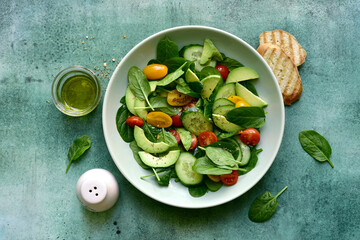Fresh vegetables salad with spinach, avocado, cucumber and cherry tomatoes. Top view with copy space.