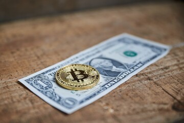 Closeup of a golden bitcoin medal on a dollar bill.