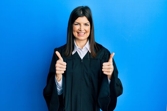 Young hispanic woman wearing judge uniform success sign doing positive gesture with hand, thumbs up smiling and happy. cheerful expression and winner gesture.