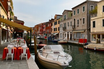 Fototapeta na wymiar Burano Island Canal with Sidewalk Dining and Boats in Canal