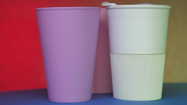 Purple white and pink beverage cups rotate on blue table under coloured lights at celebration close view. Concept beer pong