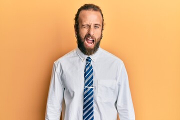 Handsome man with beard and long hair wearing business clothes winking looking at the camera with sexy expression, cheerful and happy face.