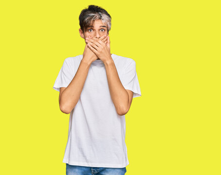 Young hispanic man wearing casual white tshirt shocked covering mouth with hands for mistake. secret concept.