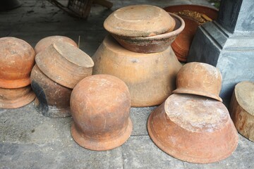 Fototapeta premium Vintage fired clay bowls and pots stacked on a stone floor in rural Southeast Asia