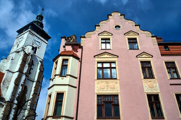 Obraz premium The facade of a historic tenement house and the belfry of a medieval church in the town of Zlotoryja