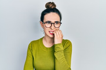 Young hispanic girl wearing casual clothes and glasses looking stressed and nervous with hands on mouth biting nails. anxiety problem.