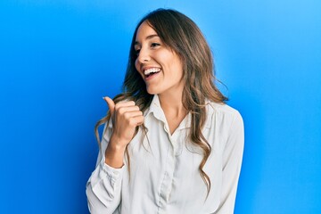 Fototapeta premium Young brunette woman wearing casual clothes pointing thumb up to the side smiling happy with open mouth