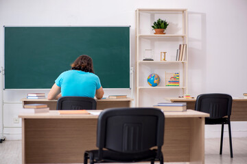 Young male student in front of green board