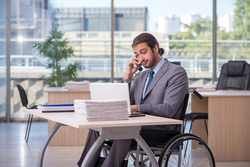 Young male employee in wheel-chair working in the office