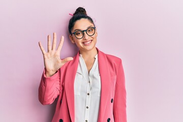 Beautiful middle eastern woman wearing business jacket and glasses showing and pointing up with fingers number five while smiling confident and happy.