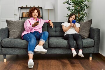 Mature mother and down syndrome daughter at home watching television and using smartphone