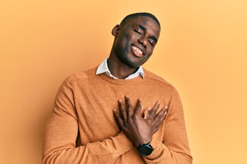 Young african american man wearing casual clothes smiling with hands on chest with closed eyes and grateful gesture on face. health concept.