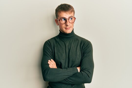 Young caucasian man wearing glasses with arms crossed gesture smiling looking to the side and staring away thinking.