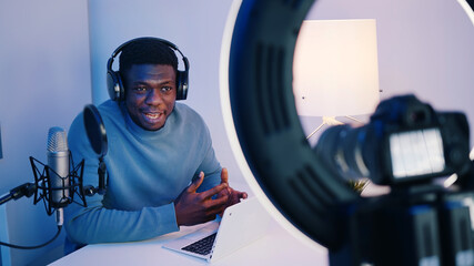 Obraz premium Close-up footage of the camera screen showing an African American man wearing headphones sitting at the table explaining something. Concept of online classes or podcasts. . High quality photo