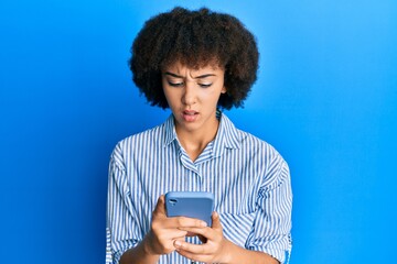 Young hispanic girl using smartphone clueless and confused expression. doubt concept.