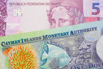 A macro image of a pink and purple five real bank note from Brazil paired up with a colorful one dollar note from the Cayman Islands.  Shot close up in macro.
