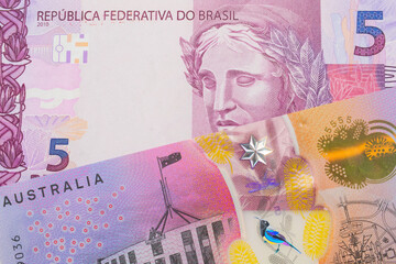A macro image of a pink and purple five real bank note from Brazil paired up with a colorful five dollar bill from Australia.  Shot close up in macro.