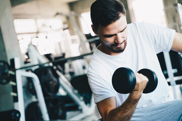 Fototapeta na wymiar Smart sport man lifting dumbbell up in fitness gym wellnes activity