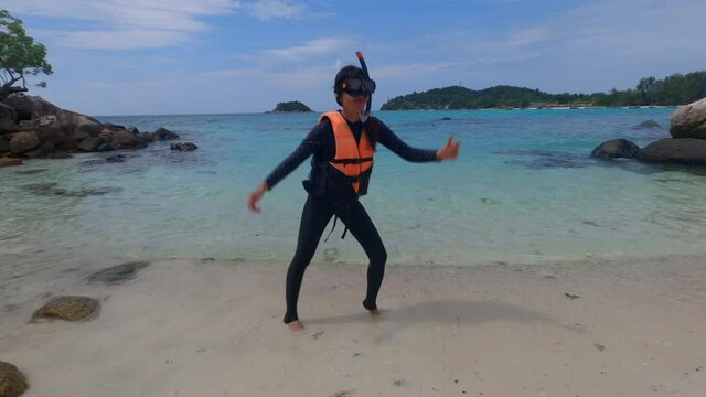 Asian woman elvis dancing at the beach against a daytime sea backdrop