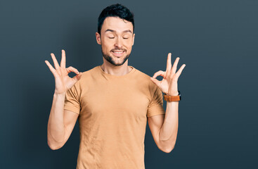 Hispanic man with beard wearing casual t shirt relaxed and smiling with eyes closed doing meditation gesture with fingers. yoga concept.