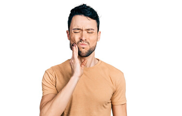 Hispanic man with beard wearing casual t shirt touching mouth with hand with painful expression because of toothache or dental illness on teeth. dentist