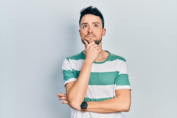 Young hispanic man wearing casual clothes with hand on chin thinking about question, pensive expression. smiling with thoughtful face. doubt concept.