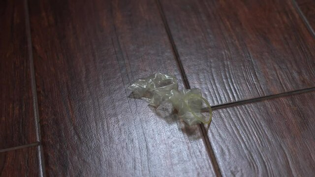 Close-up of a used condom falling to the floor