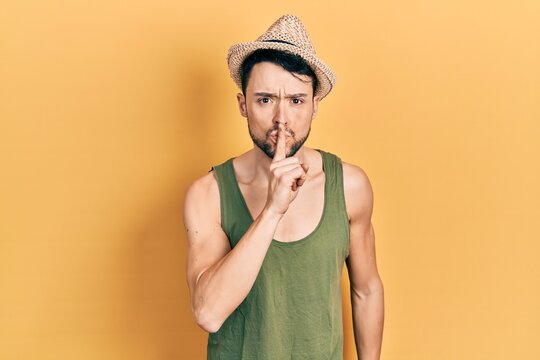 Young hispanic man wearing summer hat asking to be quiet with finger on lips. silence and secret concept.