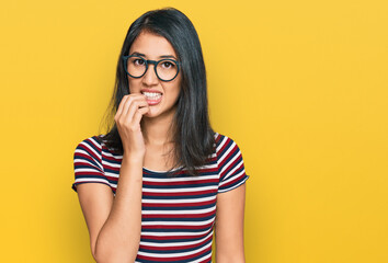 Beautiful asian young woman wearing casual clothes and glasses looking stressed and nervous with hands on mouth biting nails. anxiety problem.