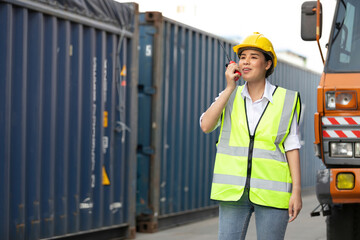 woman factory worker or engineer using walkie talkie for preparing a job in containers warehouse storage