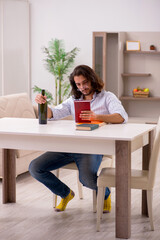 Young male student drinking alcohol at home