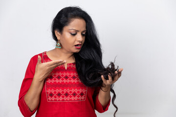 Portrait of Indian woman with long hair facing hair fall problem, hair loss, holding hair in hand, dandruff problem, alopecia.