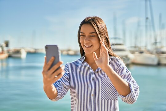 Young hispanic girl smiling happy doing video call using smartphone at the port