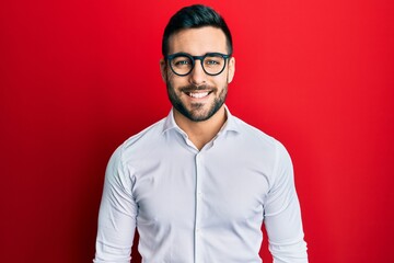 Young hispanic businessman wearing shirt and glasses happy face smiling with crossed arms looking...