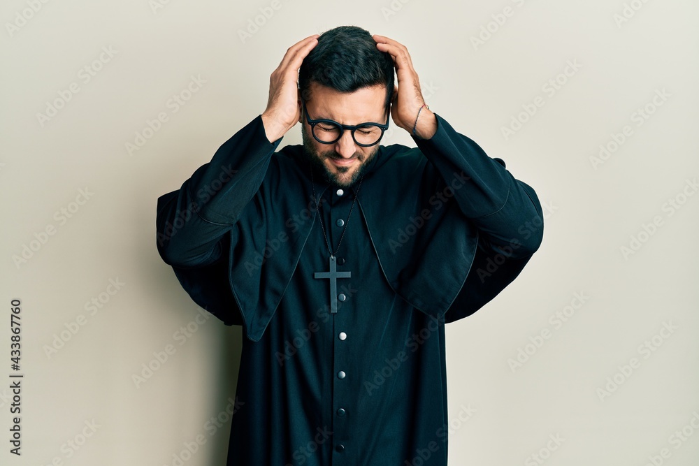 Wall mural Young hispanic man wearing priest uniform standing over white background suffering from headache desperate and stressed because pain and migraine. hands on head.